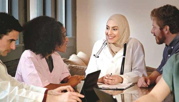 A Muslim female doctor leading a young multi-ethnic medical team in a modern office setting.
