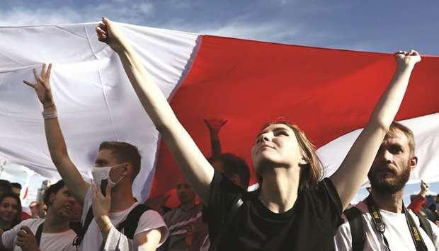 Opposition supporters carry a huge white-red-white flag of Belarus, which was in use prior to the current one, during a rally to protest in Minsk.