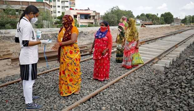A healthcare worker puts a pulse oximeter on a woman's finger to check her oxygen level during a survey for the coronavirus disease at a construction site of a railway track, in Babla village on the outskirts of Ahmedabad