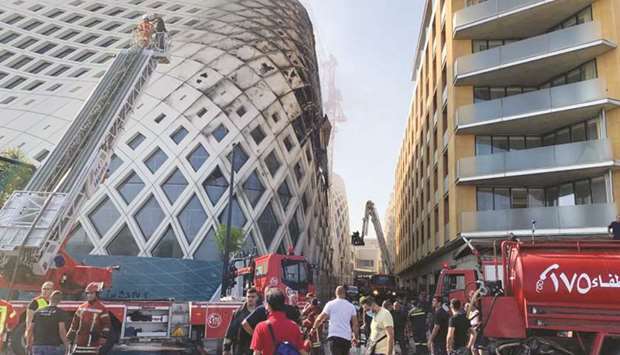 Firefighters and people gather near the site of a fire that broke out in a building in Central Beirut yesterday.