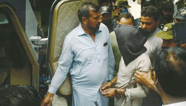 Policemen escort Shafqat Ali (face covered), one of two suspects in the gang-rape case, as they leave from a local court in Lahore yesterday.
