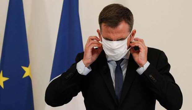 French Health Minister Olivier Veran puts on his protective mask after addresses media representatives during a press conference at The Ministry of Health in Paris yesterday, on the situation of the novel coronavirus in France