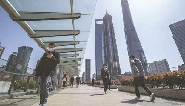 Pedestrians wearing protective masks walk through the Lujiazui Financial District in Shanghai. Global asset managers have been dazzled by the promised riches of Chinau2019s $3.4tn mutual fund industry. However, theyu2019re now learning just how fierce the local competition will be.