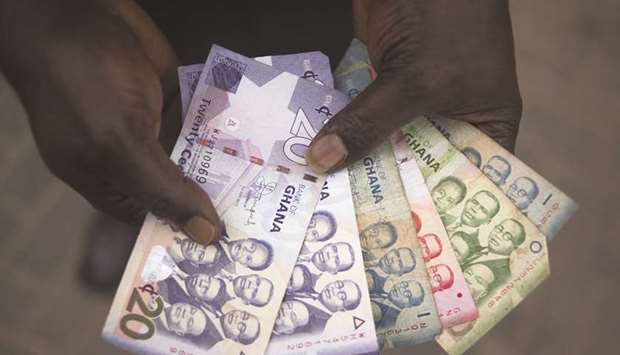 A man holds a collection of Ghana cedi banknotes in Accra. The cedi was little changed at 5.7828 per dollar yesterday. Itu2019s been trading in a range around that level since rebounding from a decline to a record 6.0401 in the wake of the Covid-19 sell-off in April.