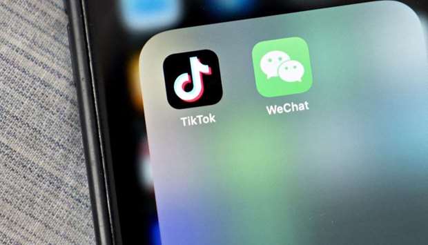 The WeChat and TikTok app icons are displayed on a smartphone in an arranged photograph taken in Arlington, Virginia. The US bans, announced yesterday, affect only new downloads and updates and are less sweeping than expected, particularly for TikTok, giving its parent group ByteDance some breathing space to clinch an agreement over the fate of its US operations. WeChat, an all-in-one messaging, social media and electronic payment app, faces more severe restrictions from tomorrow.