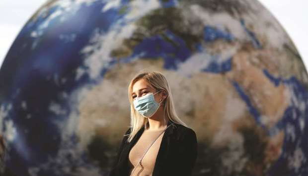 A woman wearing a face mask stands in front of a giant inflatable model of planet Earth as the spread of the coronavirus disease continues in Prague, Czech Republic on September 19.