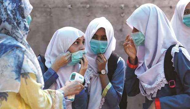 This picture taken earlier this week shows students adjusting their masks as they get their temperature checked before entering class at a school in Karachi.
