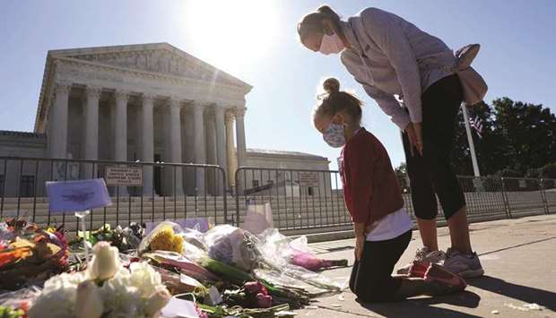 Five-year-old Abby Martin of Arlington, Virginia, pays respect with her mother Jackie Martin as they visit a makeshift memorial in front of the US Supreme Court for the late Justice Ruth Bader Ginsburg in Washington, DC yesterday. Justice Ginsburg died last Friday from complications of pancreatic cancer at the age of 87.