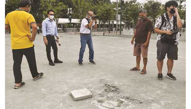 People take photos at an empty space in Bangkok yesterday, where a commemorative plaque was placed by pro-democracy protest leaders on Sunday.