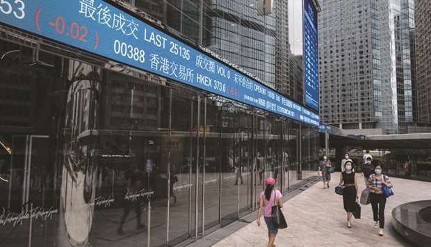 Pedestrians walk past an electronic ticker displaying share prices of Hong Kong Exchanges & Clearing Ltd at the Exchange Square complex. Hong Kong led losses on Asia markets, dropping 2.1% at 23,950.69 points yesterday.