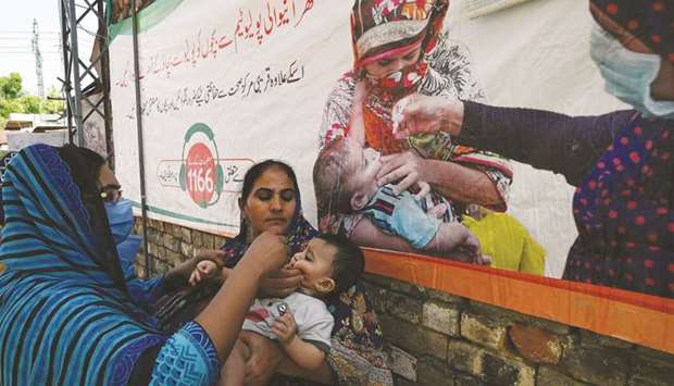 A health worker administers polio vaccine drops to a child during a door-to-door vaccination campaign at a low-income residential area in Islamabad.