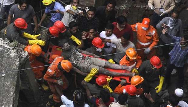 Rescue workers carry a survivor from the rubble of a collapsed three-storey residential building in Bhiwandi yesterday.