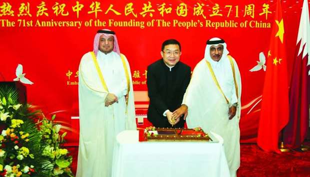 HE the Minister of Transport and Communications Jassim Seif Ahmed al-Sulaiti and Chinese ambassador Zhou Jian cut a cake at the event yesterday as Qatar's Ministry of Foreign Affairs Protocol Department director Ibrahim Yousif Fakhro looks on. PICTURE: Ram Chand.
