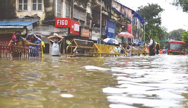 Commuters wade through a flooded street following heavy monsoon rains in Mumbai yesterday.