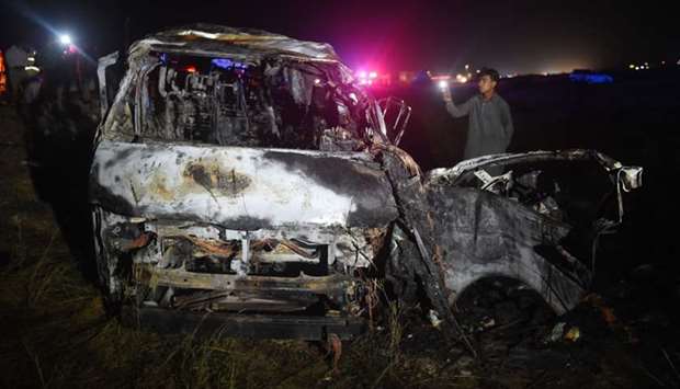 A man looks on at the wreckage of a burnt passenger van following an overnight accident in the Nooriabad area on a highway some 50 kilometers from Pakistan's port city of Karachi late on September 26