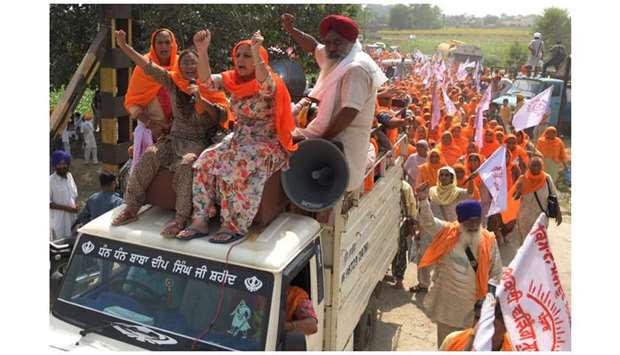 Farmers shout slogans as they arrive to block railway tracks during a protest.