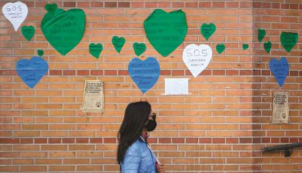 A woman walks past notices in the shape of hearts, reading u2018SOS Public Heatlhcareu2019, outside a health centre in Madrid. A million Madrid residents were under partial lockdown as the region moved to slow the spread of new infections, drawing fire from the Spanish government for not going far enough.