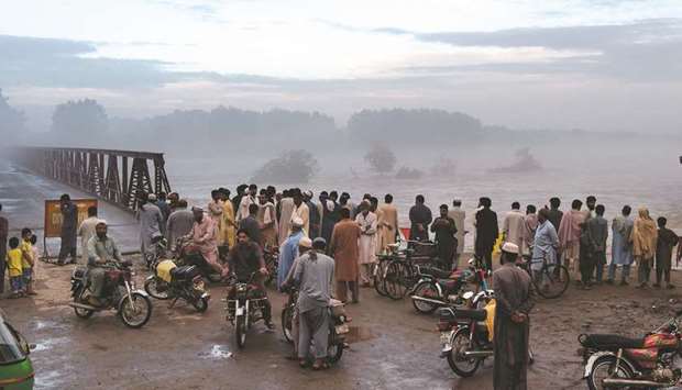 Local residents gather to watch the swollen Charsadda river following heavy monsoon rainfall, on the outskirts of Peshawar.
