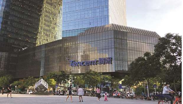 People are seen in front of the Tencent company headquarters in Shenzhen. Alibaba and Tencent are wrestling for online leadership in everything from social entertainment to e-commerce and cloud computing. The key to winning the war is to control the means through which a billion Chinese spend their money online.
