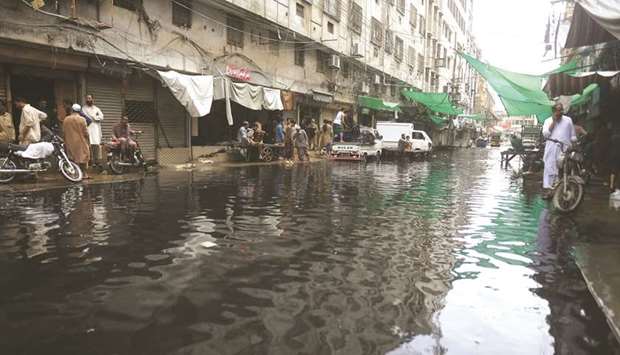 This picture taken late last month shows people in front of closed shops along a flooded street in Karachi.
