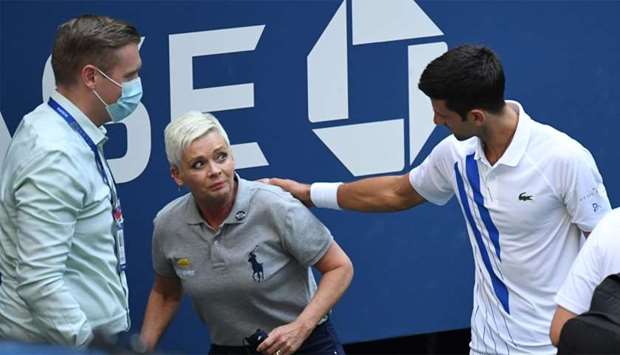 Novak Djokovic of Serbia and a tournament official tend to a linesperson who was struck with a ball by Djokovic against Pablo Carreno Busta of Spain (not pictured) on day seven of the 2020 US Open tennis tournament at USTA Billie Jean King National Tennis Center.