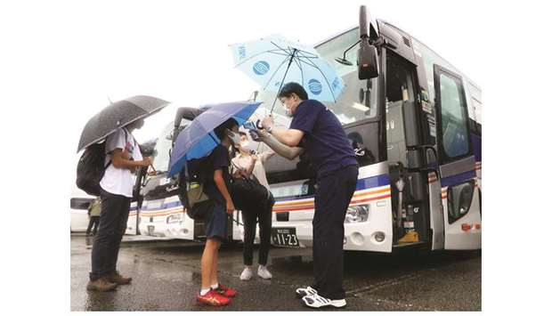 People undergo a temperature check before boarding a bus as an evacuation advice is issued due to the approach of typhoon Haishen in Hitoyoshi, Kumamoto Prefecture yesterday.