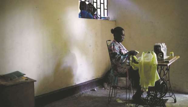 A woman checks clothes as she sits at a sewing machine operated by foot pedal, in Port-au-Prince, Haiti, in this July 24 photograph.