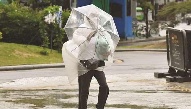 A man struggles to hold onto his umbrella as he walks against strong winds caused by Typhoon Haishen in central Seoul yesterday.