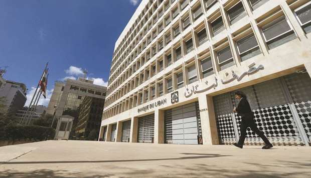 A woman walks outside of Lebanonu2019s central bank building in Beirut (file). Crushed by a mountain of debt, Lebanonu2019s financial system crumbled in 2019, with banks shutting out customers from deposits while the local currency went into tailspin.