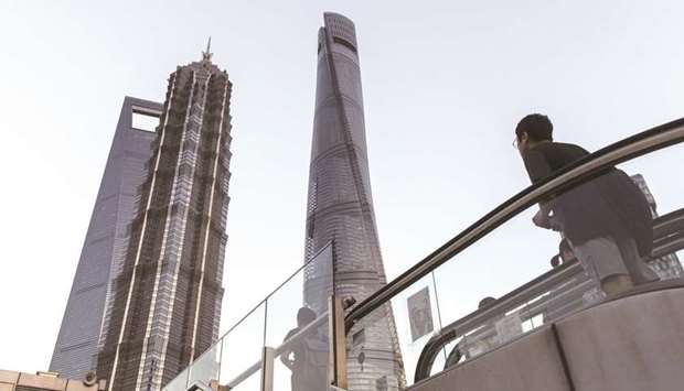 A man rides an escalator up under the skyscrapers of Pudong in Shanghai.