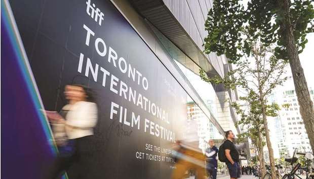 People walk past a Toronto International Film Festival (TIFF) sign in Toronto.