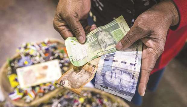 A vendor counts out rand banknotes while working in an African craft market in the Rosebank district of Johannesburg (file). The rand has reclaimed its position as the best performing emerging market currency this year after being knocked off the top spot during last monthu2019s bout of volatility.