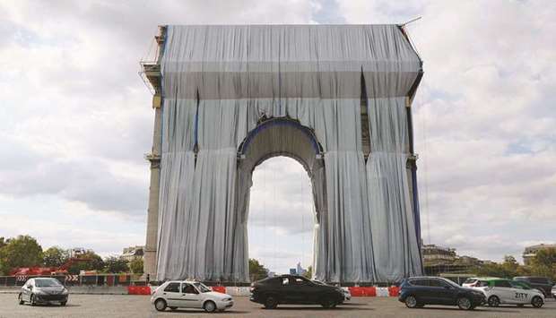 Workers unravel silver blue fabric u2013 part of the process of wrapping Lu2019Arc de Triomphe in Paris u2013 designed by the late artist Christo.