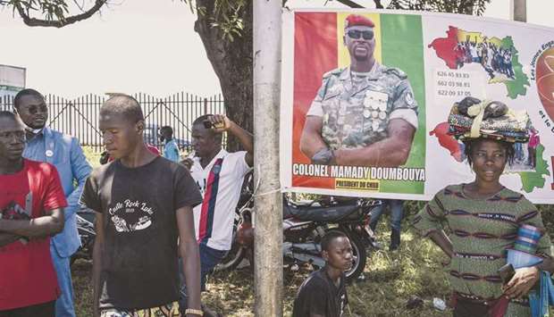 Supporters of junta leader, Colonel Mamady Doumbouya, stand around a poster of him at the Peopleu2019s Palace in Conakry.