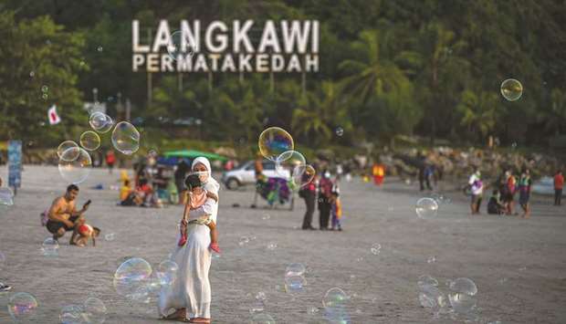 Visitors walk at Pantai Cenai in Langkawi, yesterday, as the Malaysian holiday island reopens to domestic tourists following closures due to restrictions to halt the spread of the Covid-19 coronavirus.