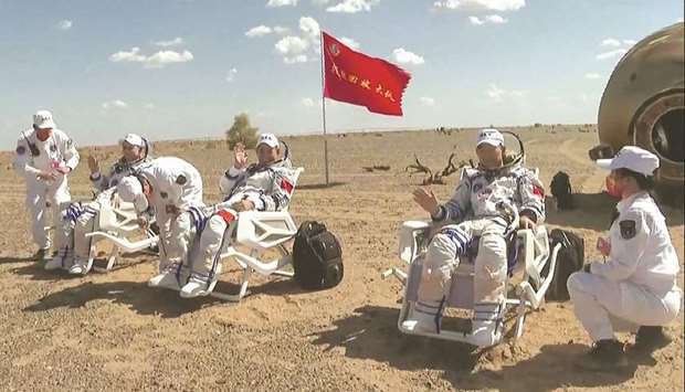 Chinese astronauts Tang Hongbo, Nie Haisheng and Liu Boming being inspected by medical personnel outside the landing capsule in the Gobi desert yesterday.