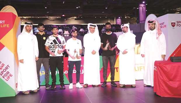 Head of the QOC sports activities and programmes Nasser al-Mudahka and Tournament Director Abdulaziz al-Ghanim pose with the winners of the 15th edition of Electronic Games Tournament (FIFA 21).
