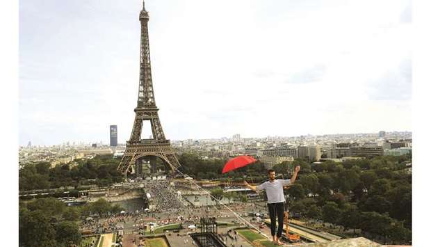 French highliner Nathan Paulin holds an umbrella yesterday as he performs, for the second time, on a 70m-high slackline spanning 670m between the Eiffel Tower and the Theatre National de Chaillot, in Paris