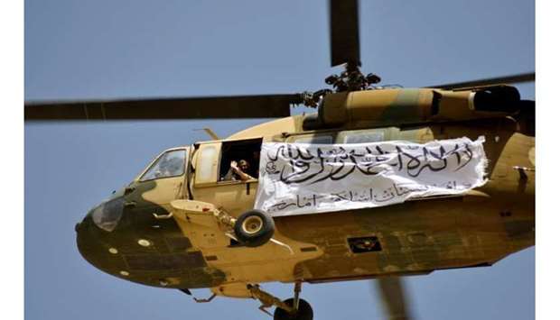A helicopter displaying a Taliban flag flies above supporters gathered to celebrate the US withdrawal from Afghanistan, in Kandahar on Wednesday. (AFP)