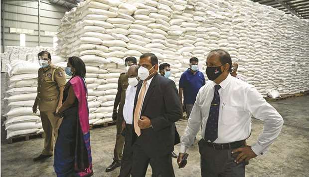 Sri Lankau2019s newly-appointed commissioner general of essential services, major general Senarath Niwunhella (in black suit) leads a raid on a sugar warehouse as part of a crackdown on hoarding in Wattala, outside Colombo, yesterday.