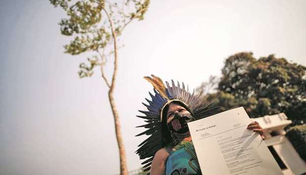 Indigenous leader Sonia Guajajara poses for a photo with a manifest letter in front of a Jatoba tree at the entrance of the Norwegian embassy in Brasilia.