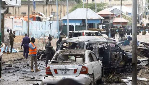 Civilians and Somalian security officers gather at the scene of a suicide car bomb at a street junction near the president's residence, in Mogadishu, Somalia.