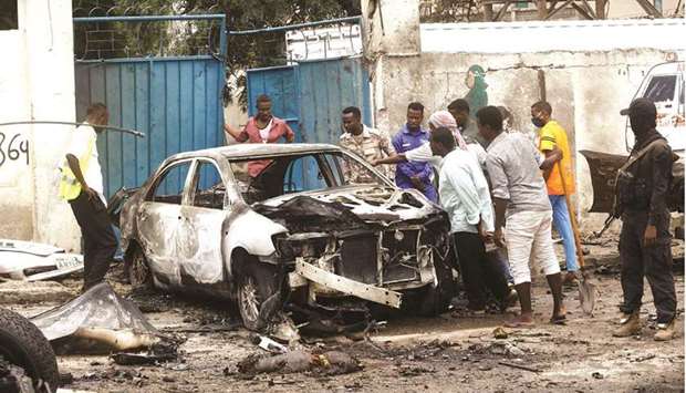 People believed to be family members of a victim look inside a damaged car at the scene of a suicide car bomb explosion near the presidentu2019s residence, in Mogadishu.