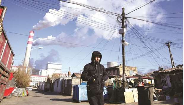A man walks near a coal-fired power plant in Harbin, Heilongjiang province (file). China is in the grip of a power crunch as a shortage of coal supplies, toughening emissions standards and strong demand from manufacturers and industry have pushed coal prices to record highs and triggered widespread curbs on usage.