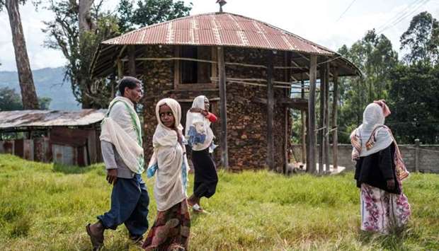 Ethiopian Orthodox devotees walk outside a church in Anderacha, formerly the site of a palace of the Kaffa kingdom, near the town of Bonga, 100 kms southwest of the city of Jimma, Ethiopia, on August 18
