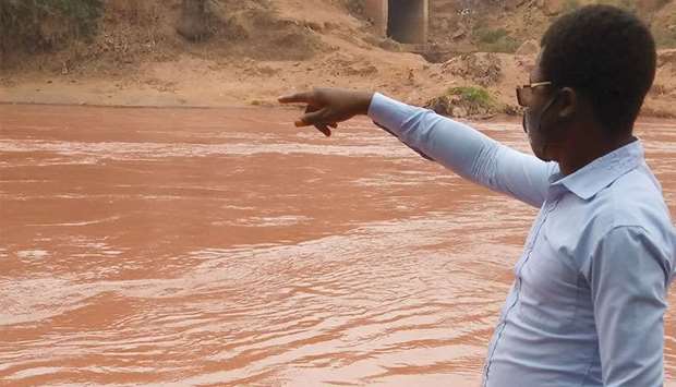 A man gestures as he looks at the Tshikapa river after it turned red, in Tshikapa City, Kasai Province, Democratic Republic of Congo, in this handout picture taken on August 11, 2021.