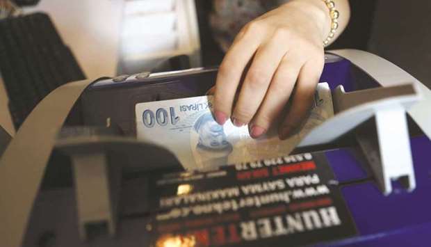 An employee of a foreign exchange office counts Turkish lira banknotes in Ankara (file). The economy is expected to expand by 9% this year before settling at about 5% growth next year, in line with outside forecasts, according to the governmentu2019s outlook set out in its so-called medium-term programme.