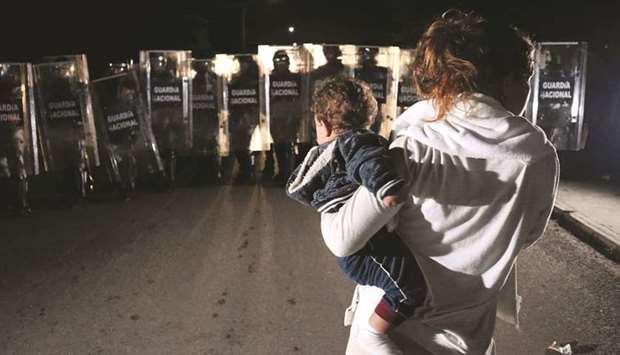 A migrant woman with a baby faces members of Mexicou2019s National Guard who are blocking the street in Huixtla, during an operation to dissolve a caravan of migrants and asylum-seekers from Central America and the Caribbean.