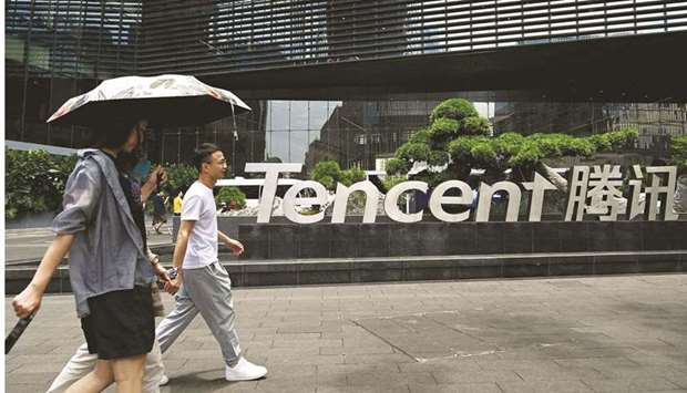 People walk past the Tencent headquarters in the southern Chinese city of Shenzhen, in Guangdong province (file). Chinese regulators summoned industry executives to a Wednesday meeting to instruct them to break their u201csolitary focusu201d on profit and prevent minors from becoming addicted to games, according to the official Xinhua News Agency.