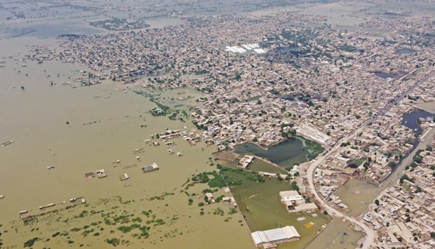 This aerial photograph taken yesterday shows a flooded residential areas after heavy monsoon rains in Jaffarabad district of Balochistan province. Right: Volunteers of Charity Al-Khidmat Foundation use a boat to distribute relief material to flood-affected people at a village on the outskirts of flood-hit area of Sukkur in Sindh province.  (AFP)